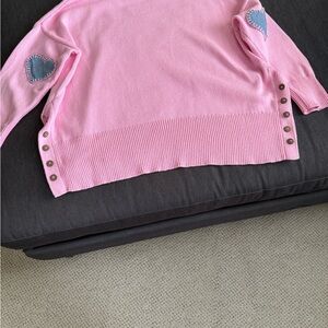 Women's Pink Sweater with blue hearts on back of sleeves.
